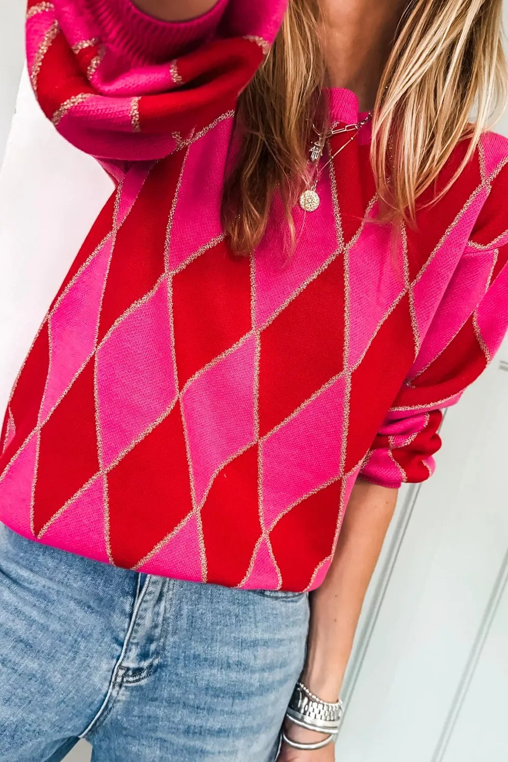 NEWYORKLISTED STYLE COLLECTION: Person wearing a red and pink argyle sweater with a white background