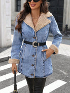NEWYORKLISTED STYLE COLLECTION: A woman wearing a light blue denim coat with a beige sherpa lining, a black belt with a silver buckle, and black leather pants, standing on a city crosswalk.