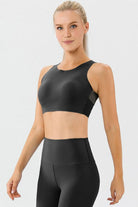 NEWYORKLISTED ACTIVEWEAR COLLECTION: Woman wearing a black athletic top and leggings on a light gray background