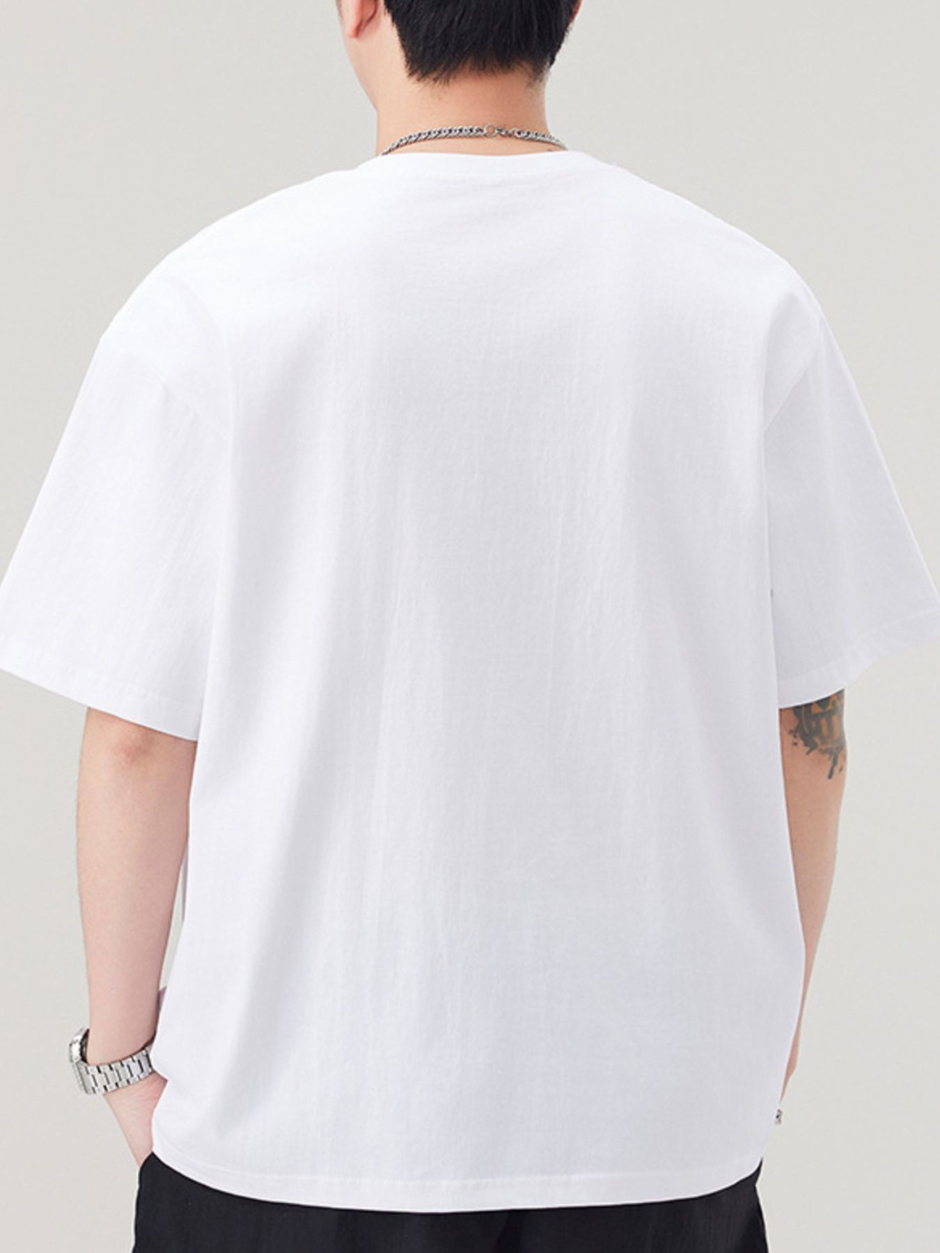 Person wearing a plain white t-shirt against a neutral background