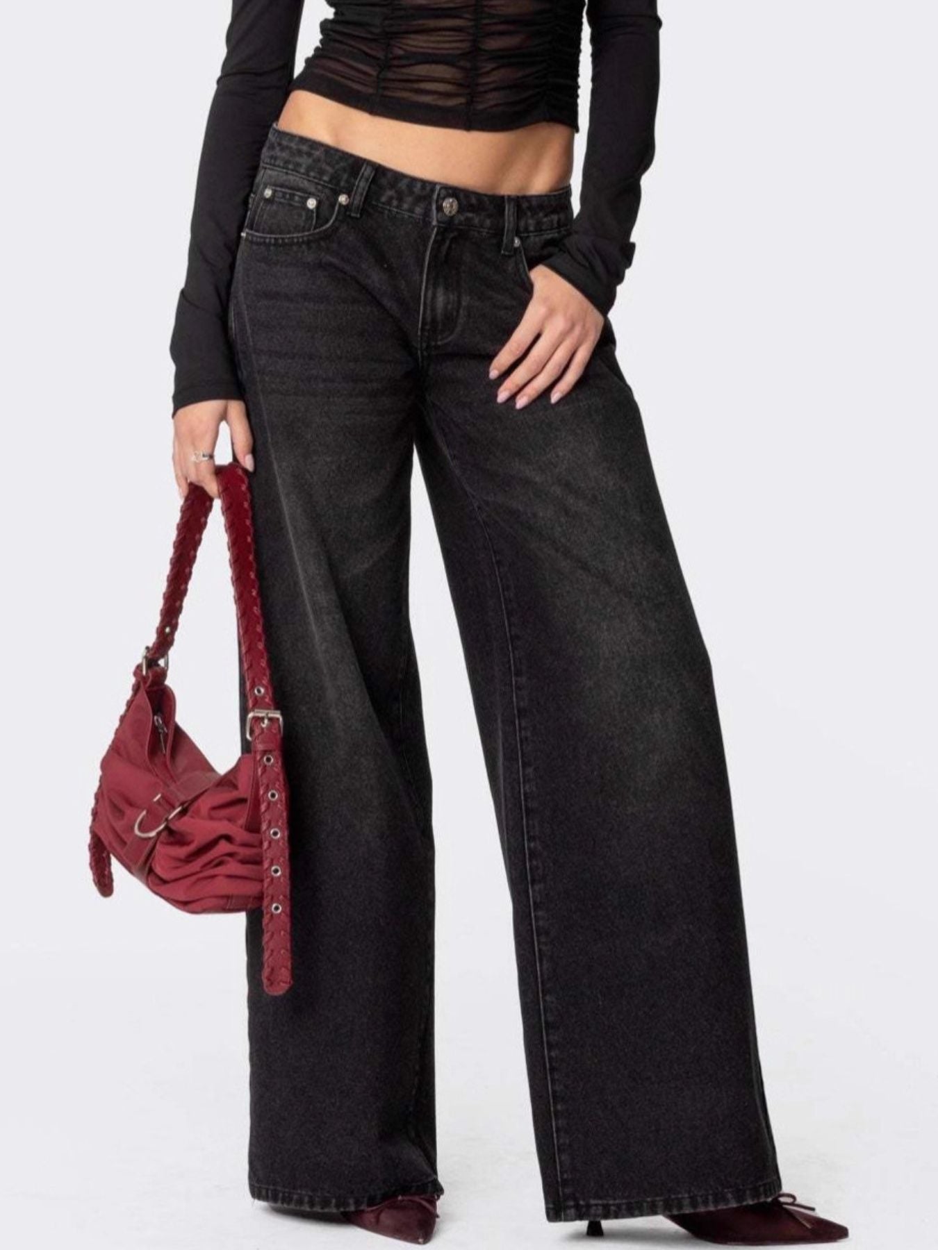 NEWYORKLISTED STYLE COLLECTION: Person wearing black wide-leg jeans and a black top, holding a red handbag on a white background
