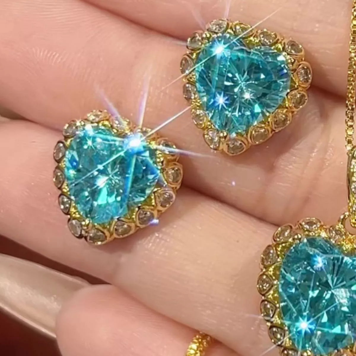 NYLD Glamour Collection by NEWYORKLISTED: Turquoise heart-shaped gemstones in gold settings held between fingers.