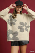 NEWYORKLISTED STYLE COLLECTION: Woman wearing a cream sweater with gray floral patterns against a red background