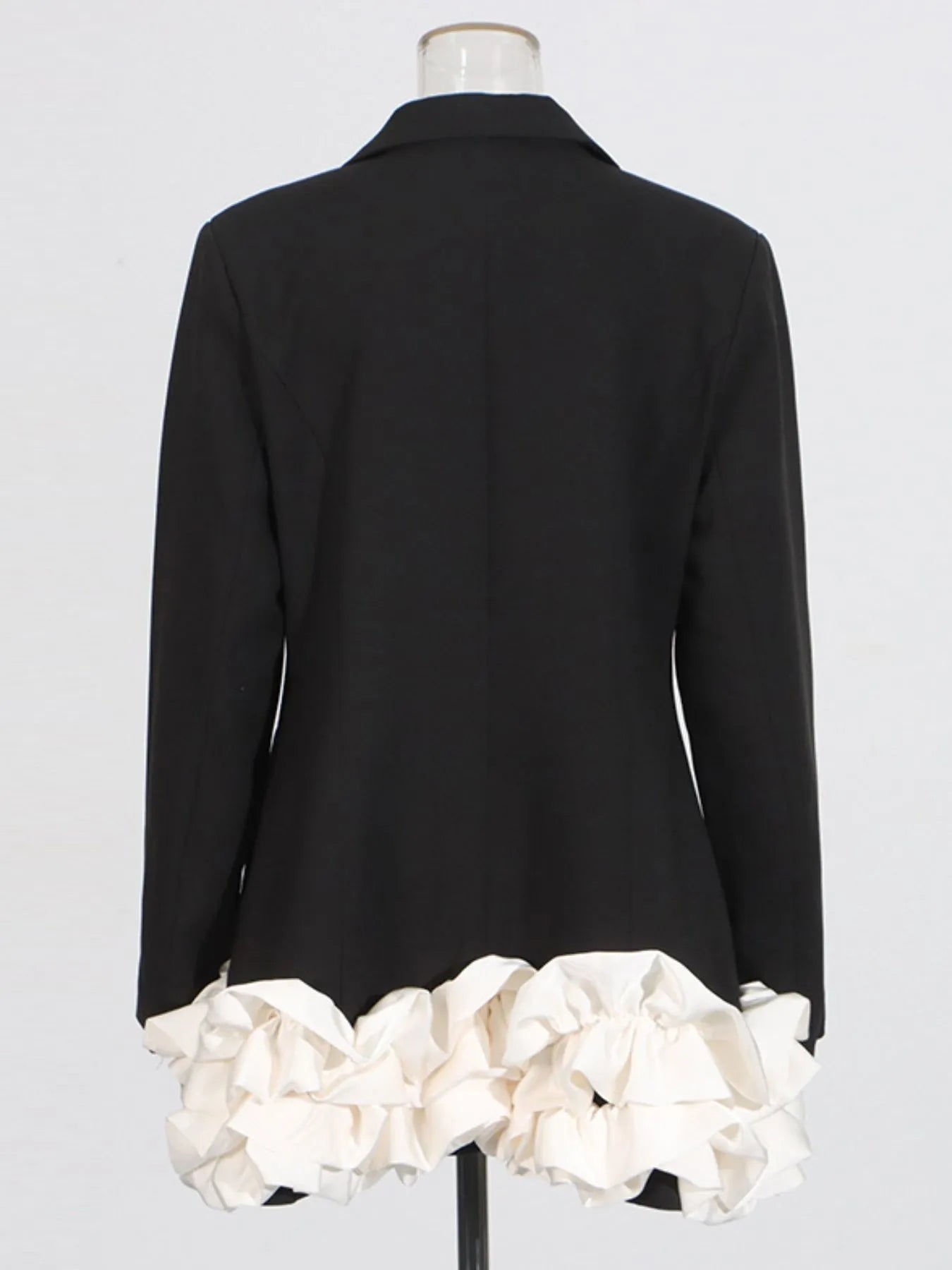 NEWYORKLISTED Runway Style: Black coat with white ruffled hem on a mannequin against a light gray background