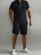 NEWYORKLISTED ATLAS MEN's COLLECTION: Male model wearing a black polo shirt and shorts with white sneakers on a gray background