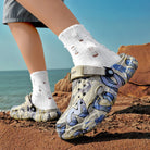 NEWYORKLISTED ATLAS MEN'S COLLECTION: Person wearing patterned shoes and white socks on a rocky beach.