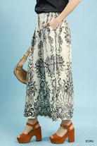 NEWYORKLISTED STYLE COLLECTION: Person wearing a patterned skirt with brown shoes and a bag on a light blue background