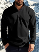 NEWYORKLISTED ATLAS MEN'S COLLECTION: Person wearing a black quarter-zip sweatshirt with a mountainous background