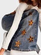 NEWYORKLISTED STYLE COLLECTION: Person wearing a denim jacket with floral embellishments on a white background