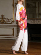 NEWYORKLSITED STYLE COLLECTION: Woman wearing a colorful floral blouse and white pants in an elegant room.