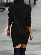 NEWYORKLISTED Style Collection: Person wearing a black dress with long sleeves and an asymmetrical hem, standing on a blurred street background.