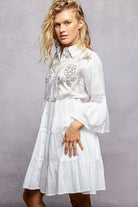 NEWYORKLISTED STYLE COLLECTION: Woman wearing a white embroidered dress against a gray background