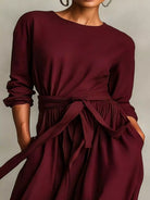 NEWYORKLISTED STYLE COLLECTION: Maroon dress with a tie waist worn by a person on a neutral background
