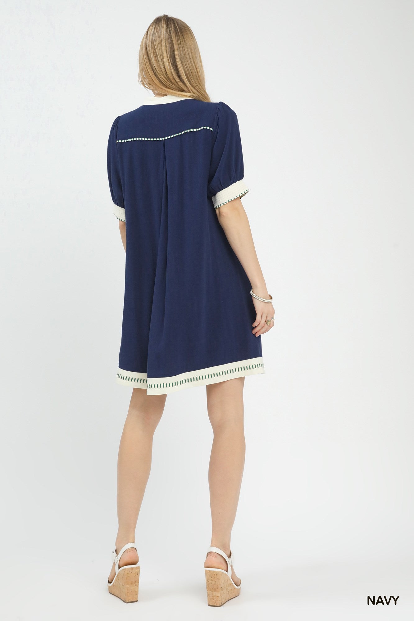 NEWYORKLISTED STYLE COLLECTION: Woman wearing a navy dress with white trim on a white background