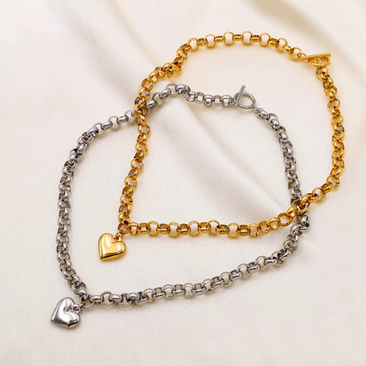 NYLD Glamour Collection by NEWYORKLISTED: Two chain bracelets, one gold and one silver, on a light fabric background.