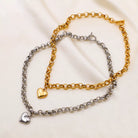 NYLD Glamour Collection by NEWYORKLISTED: Two chain bracelets, one gold and one silver, on a light fabric background.