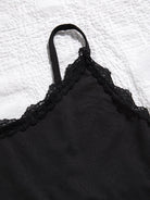 Black lace-trimmed garment on a textured white background