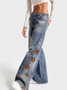 NEWYORKLISTED STYLE COLLECTION: Blue jeans with floral embellishments on a white background