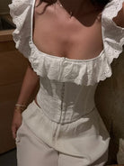 NEWYORKLISTED STYLE COLLECTION: Person wearing a white blouse with ruffled sleeves and a matching skirt.