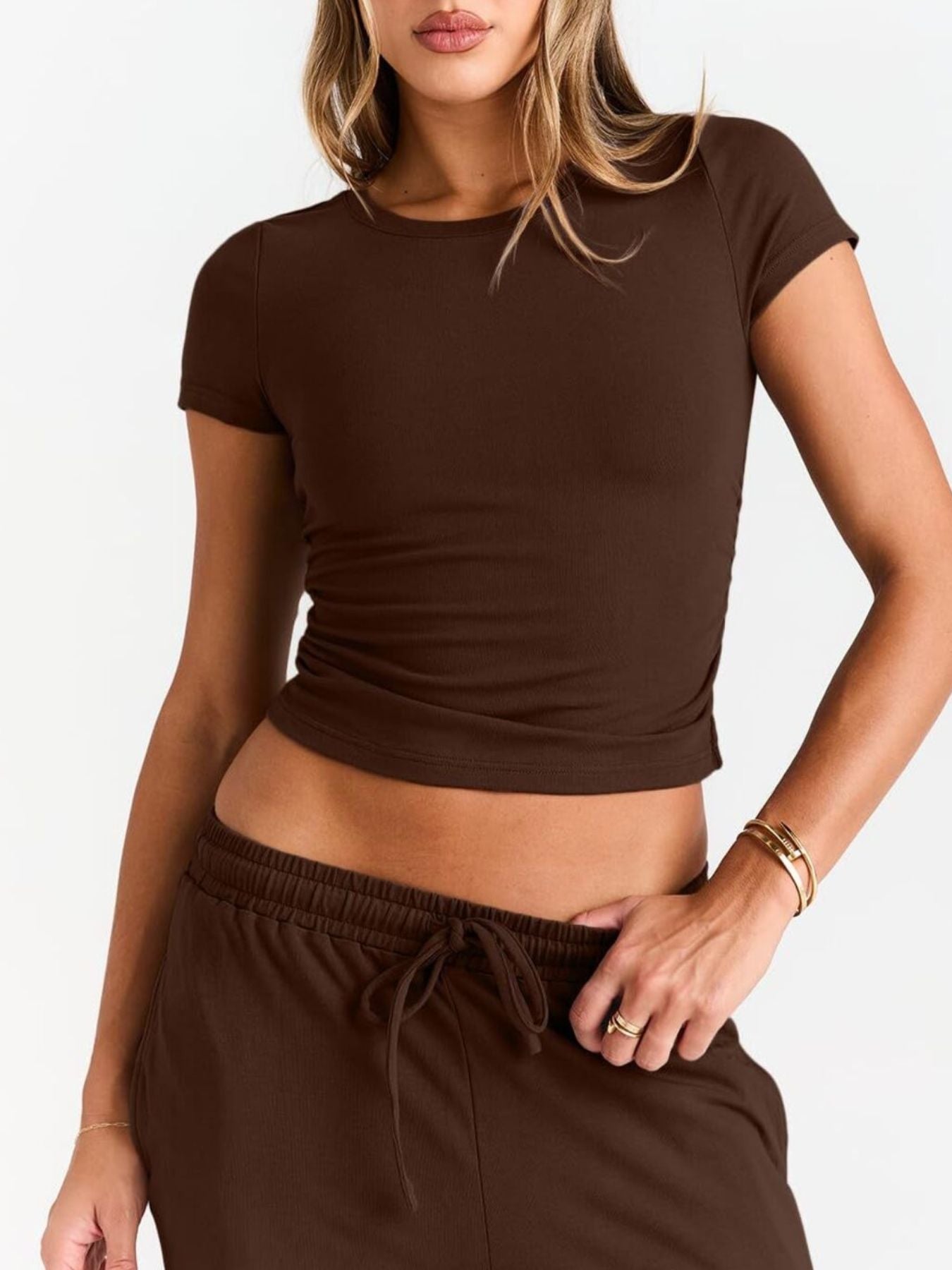 Person wearing a brown crop top and pants on a white background