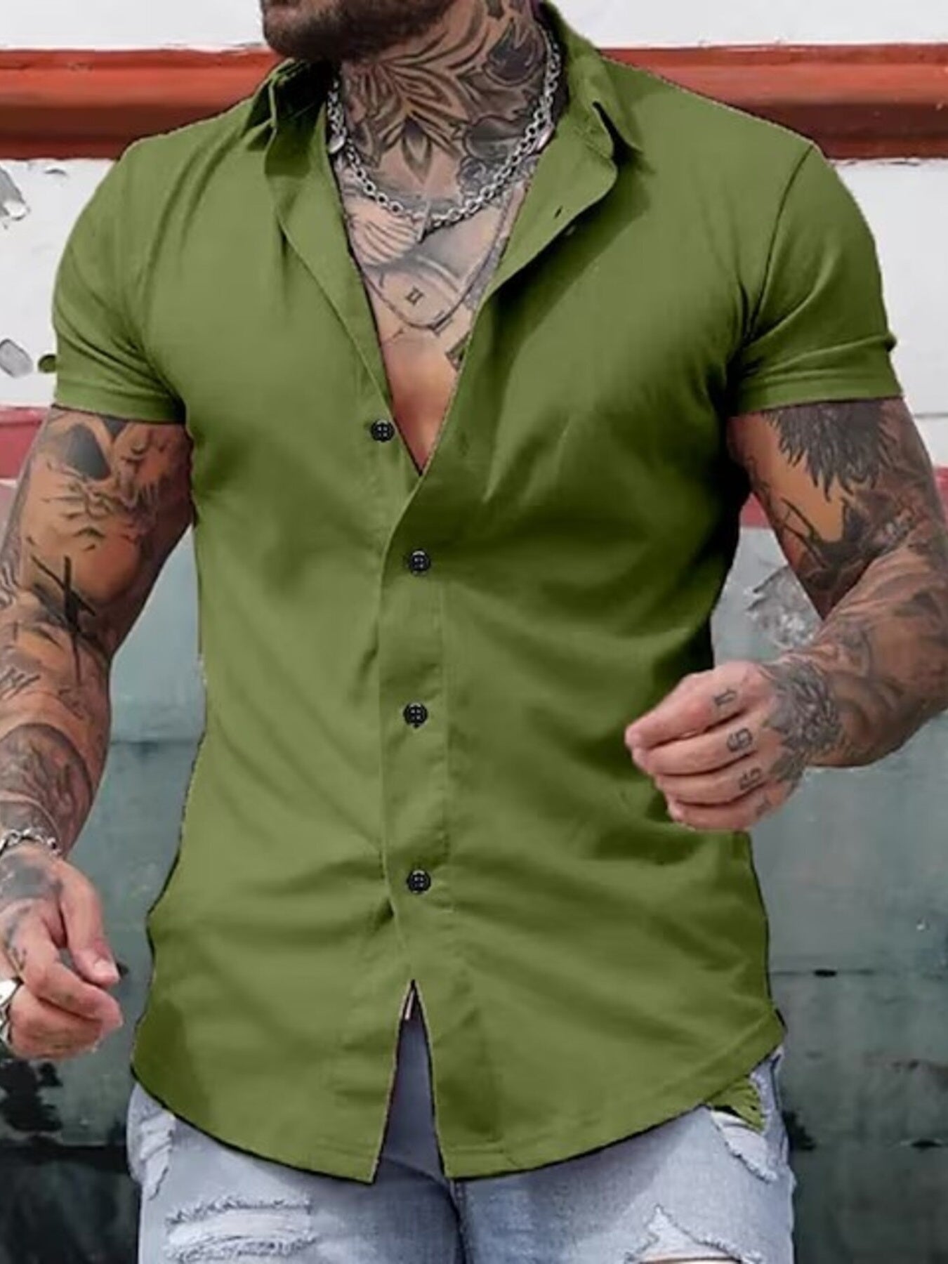 NEWYORKLISTED ATLAS MEN's COLLECTION: Man wearing a green button-up shirt with tattoos on arms and neck.