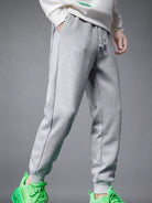 NEWYORKLISTED ATLAS MEN's COLLECTION: Gray sweatpants worn with a white top and green shoes on a gray background