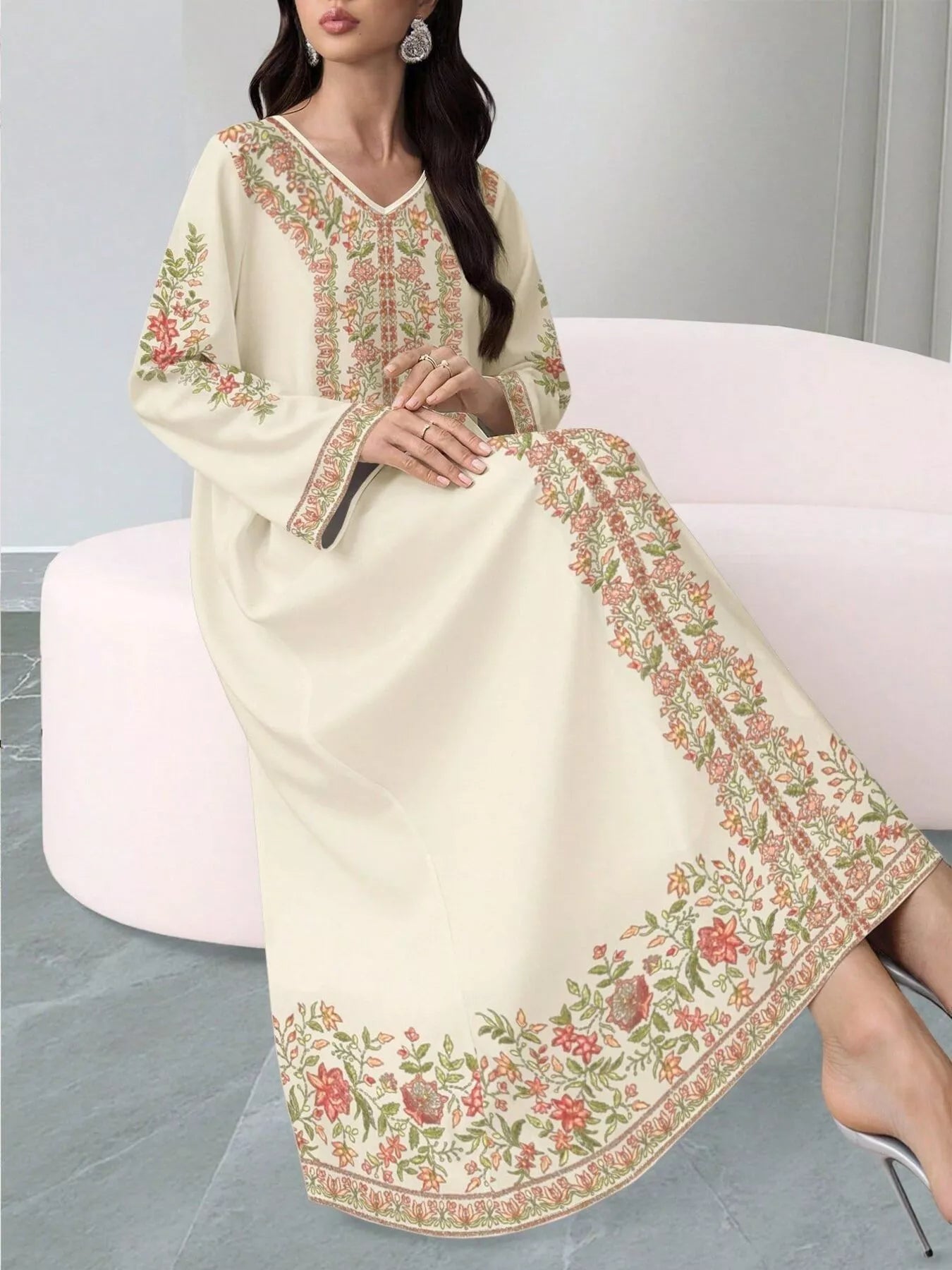 NEWYORKLISTED STYLE COLLECTION: Woman wearing a cream-colored embroidered dress sitting on a white chair.