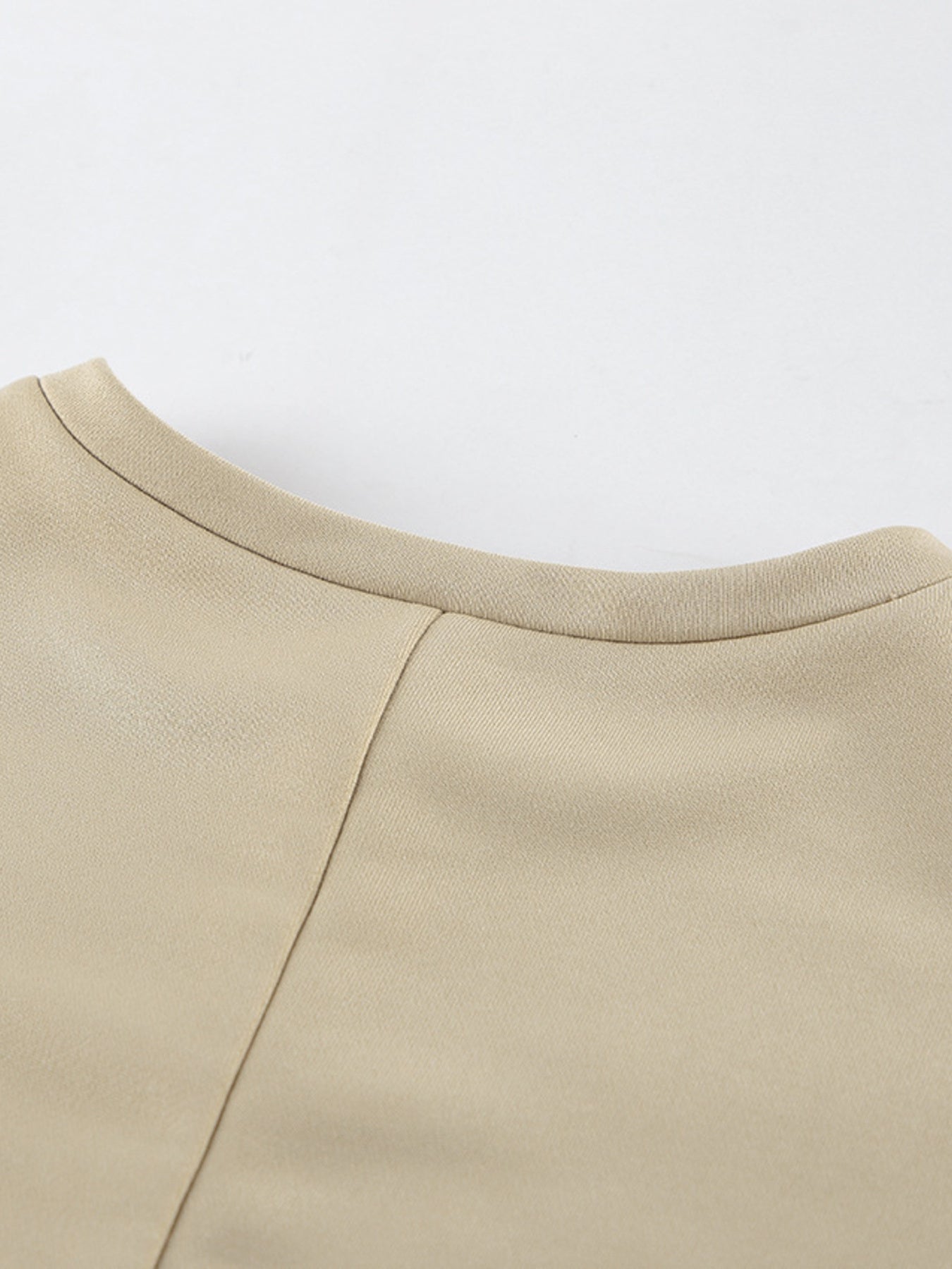 NEWYORKLISTED STYLE COLLECTION: Close-up of a beige garment with a plain background