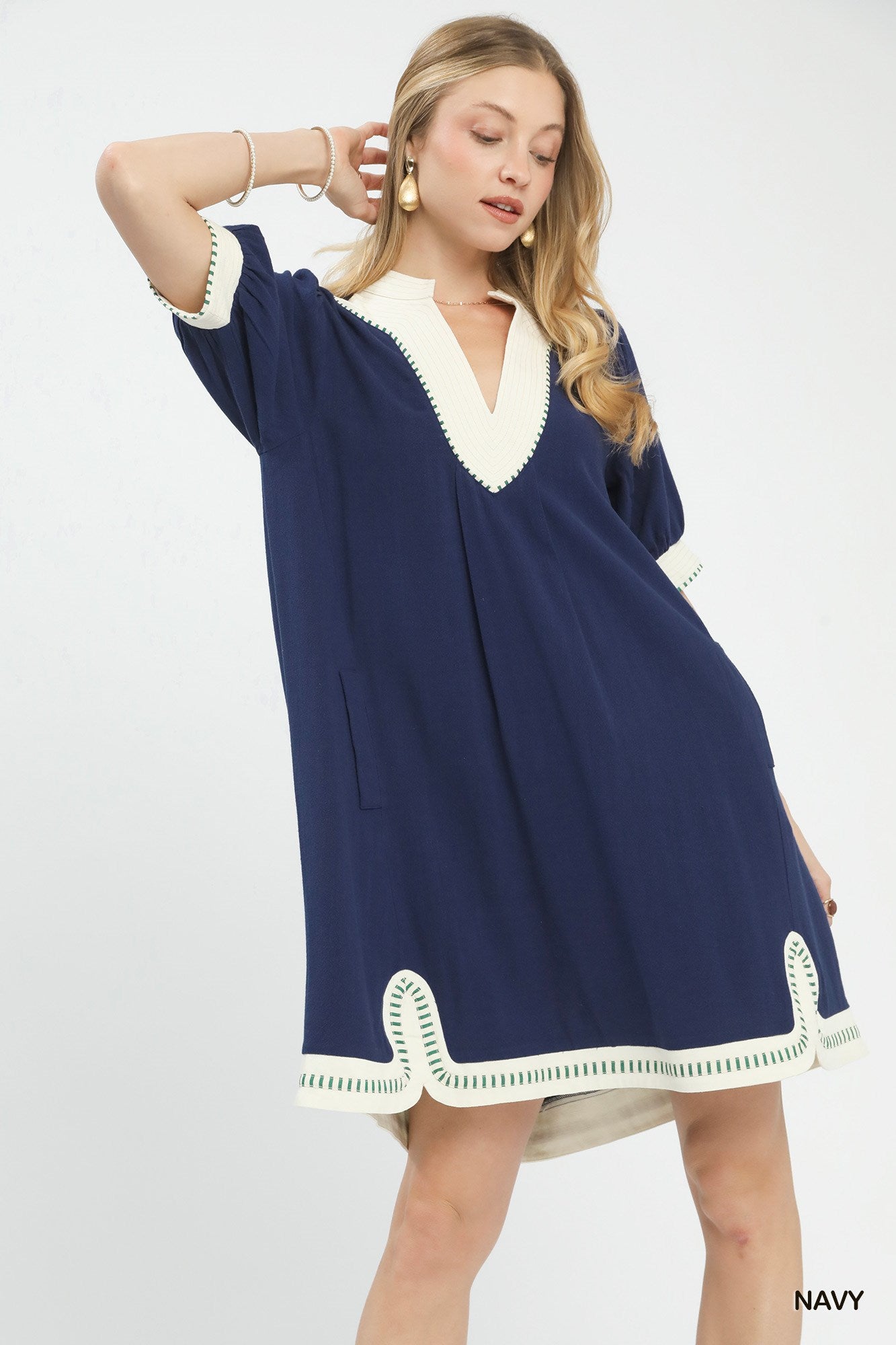 NEWYORKLISTED STYLE COLLECTION: Woman wearing a navy dress with white trim on a white background