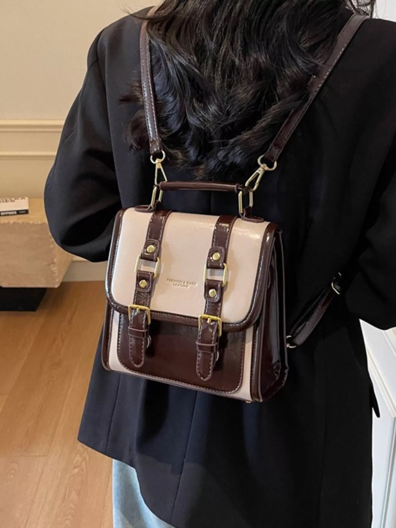 NEWYORKLISTED STYLE COLLECTION: Person wearing a white and brown leather bag over their shoulder indoors.