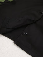 NEWYORKLISTED Intimate Apparel Collection: Close-up of a black jacket with a button on a white background