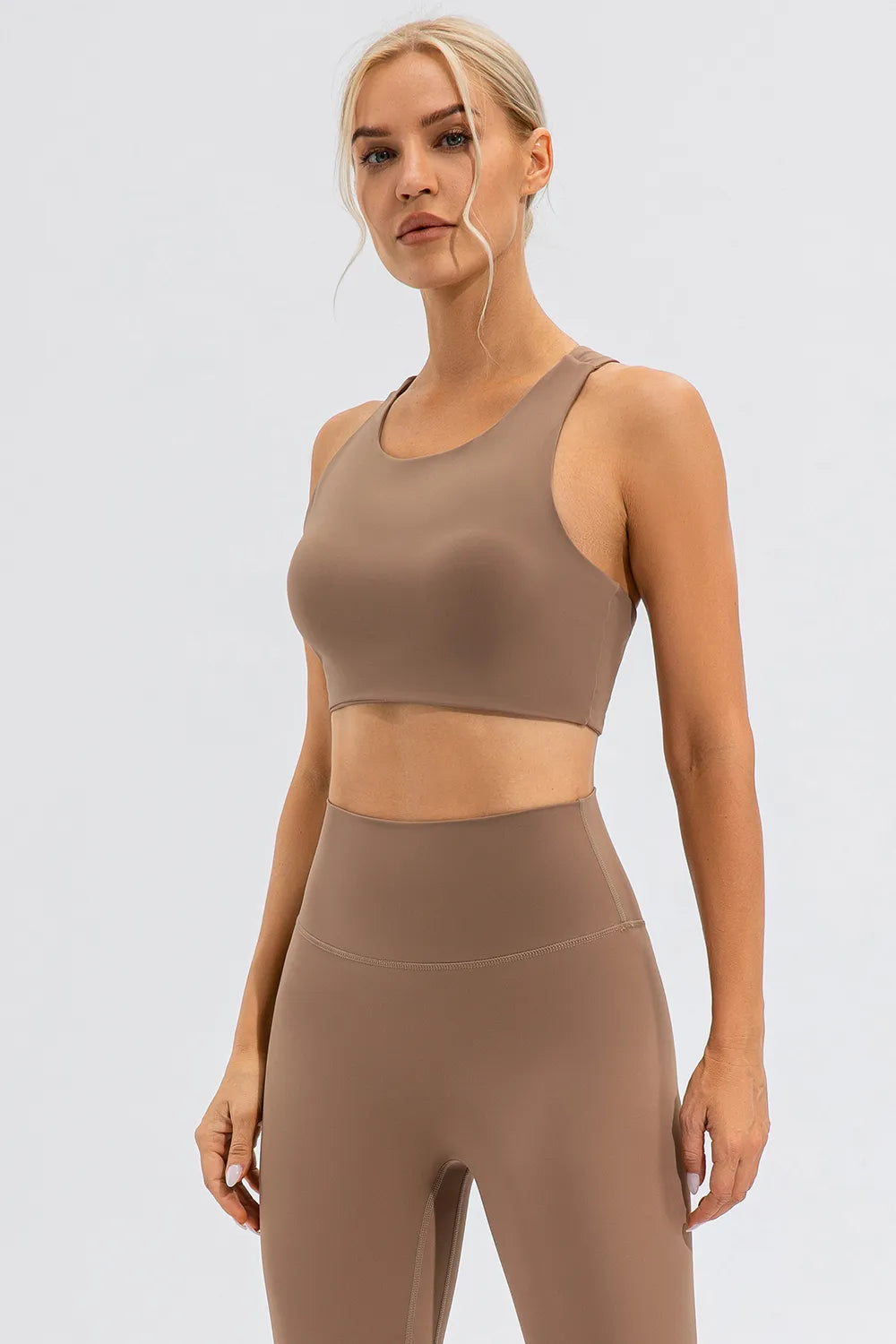 NEWYORKLISTED ACTIVEWEAR COLLECTION: Woman wearing a brown sports bra and leggings on a light gray background