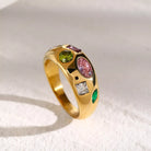 NYLD Glamour Collection by NEWYORKLISTED: Gold ring with multicolored gemstones on a textured white surface