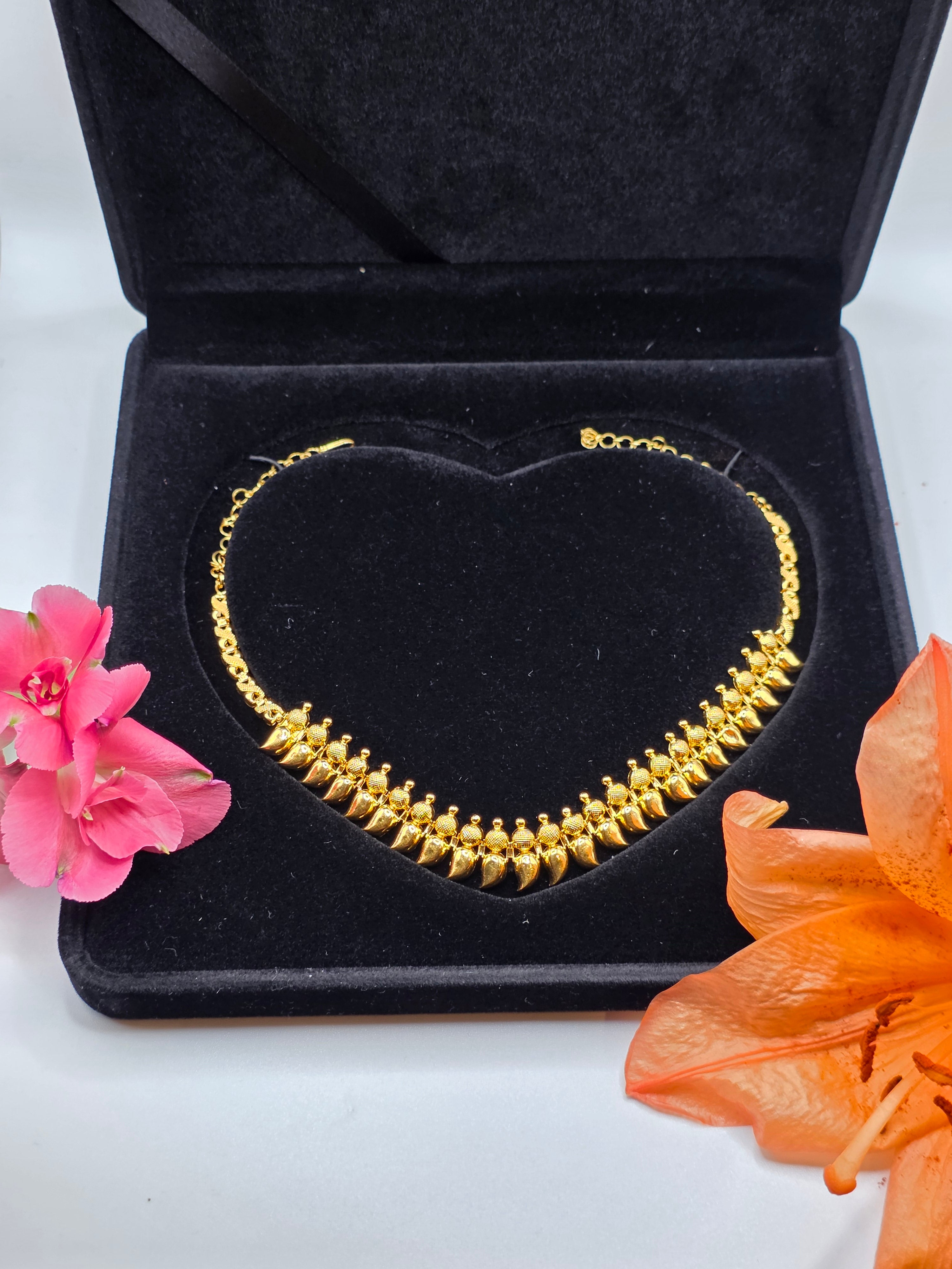 NEWYORKLISTED 22k gold necklace in a black jewelry box with pink and orange flowers on a white background