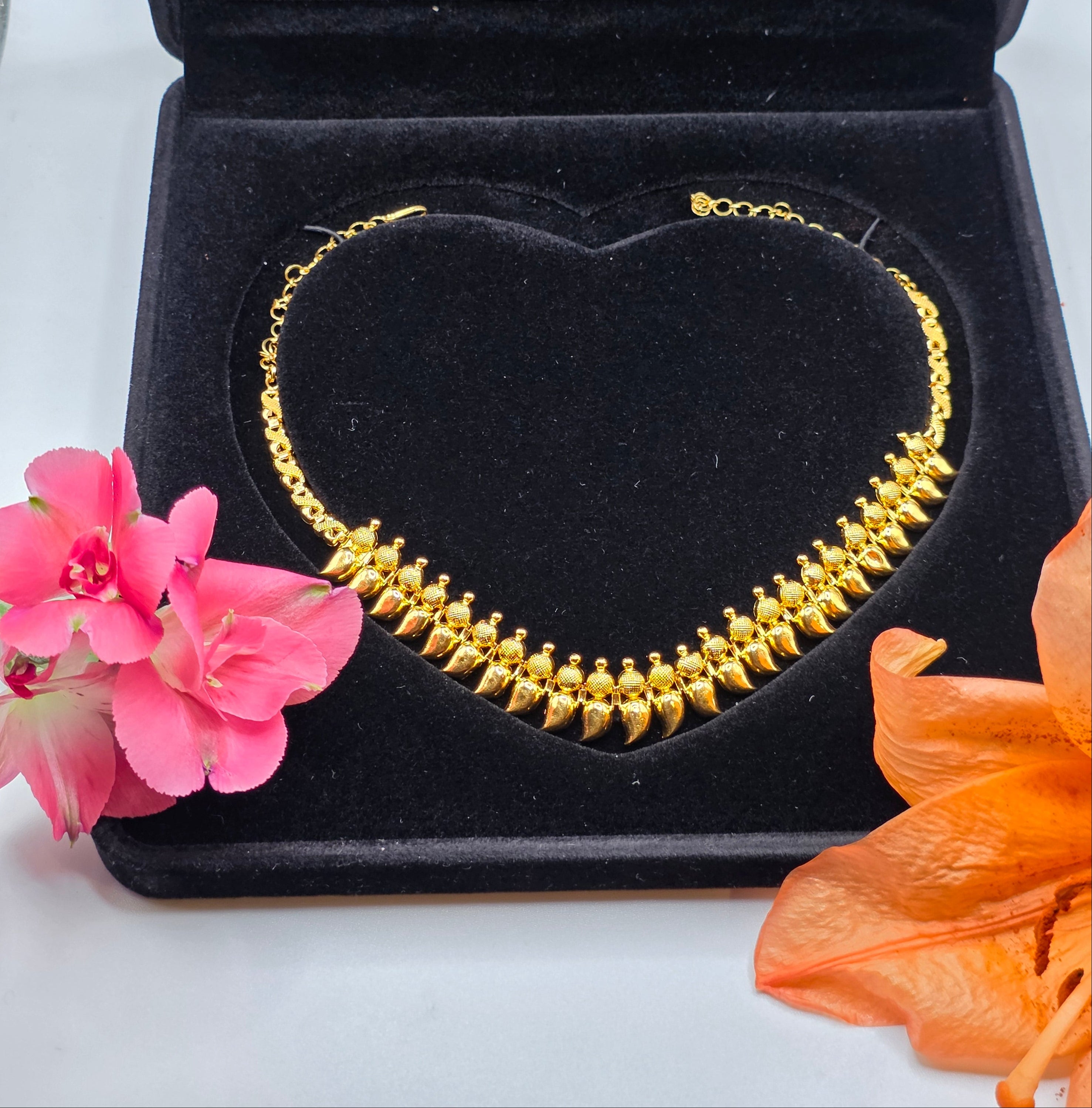 NEWYORKLISTED Valentine's Day Gifts: 22k gold necklace in a black heart-shaped box with flowers on a white background