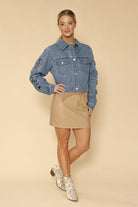 NEWYORKLISTE STYLE COLLECTION: Woman wearing a denim jacket and beige skirt on a beige background