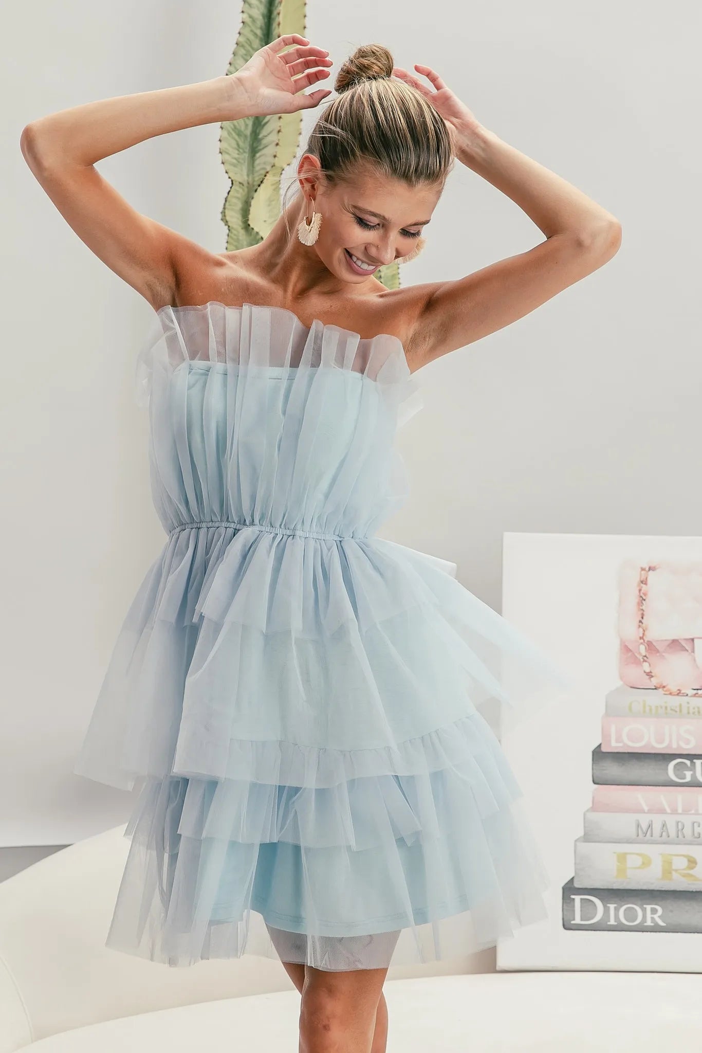 NEWYORKLISTED STYLE COLLECTION: Sleeveless Layered Organza Dress: Woman wearing a light blue strapless dress with a white background and books in the background.