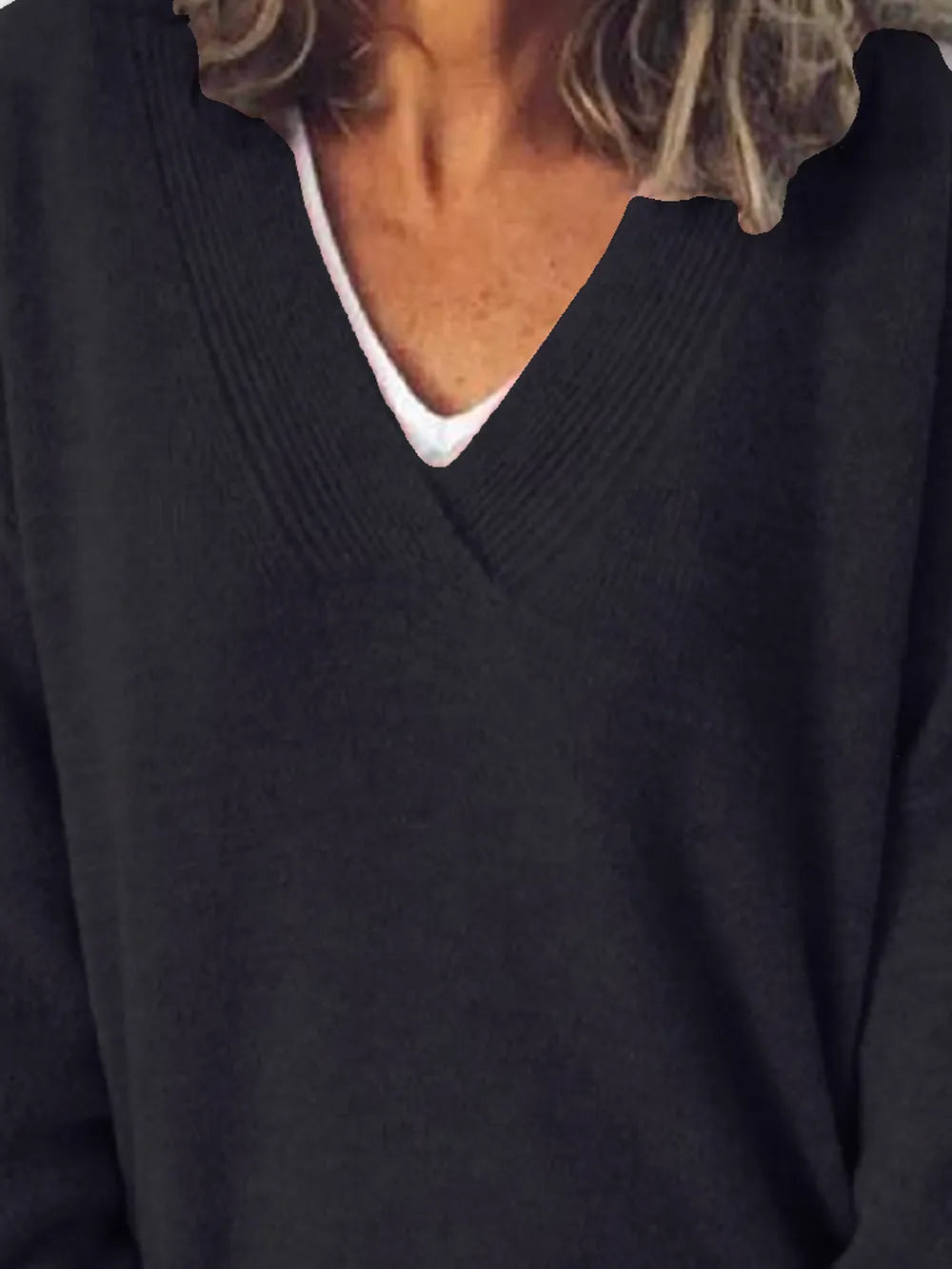 Close-up of a person wearing a dark sweater over a white shirt.