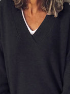 Close-up of a person wearing a dark sweater over a white shirt.