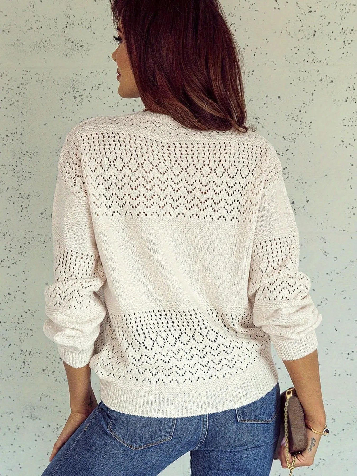 NEWYORKLISTED: Woman wearing a white lace sweater and blue jeans against a light background