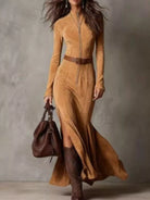 NEWYORKLISTED STYLE COLLECTION: Woman wearing a long brown dress with a belt and holding a matching handbag against a neutral background