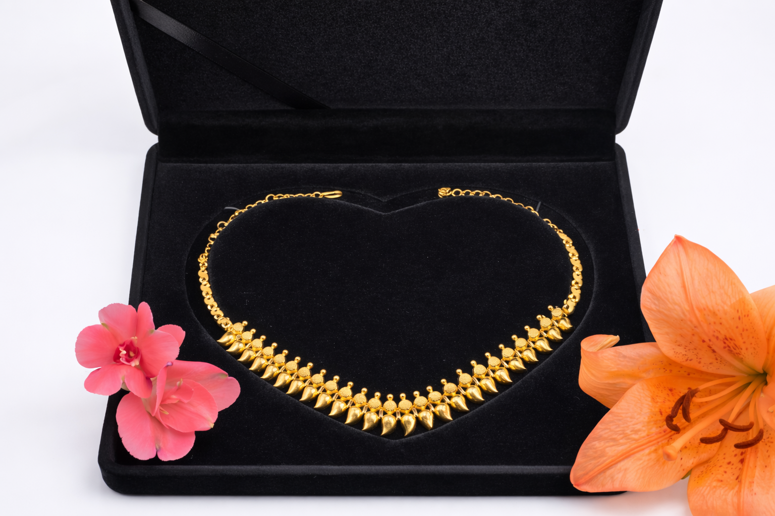 NEWYORKLISTED: 22k gold necklace in a black jewelry box with pink and orange flowers on a white background