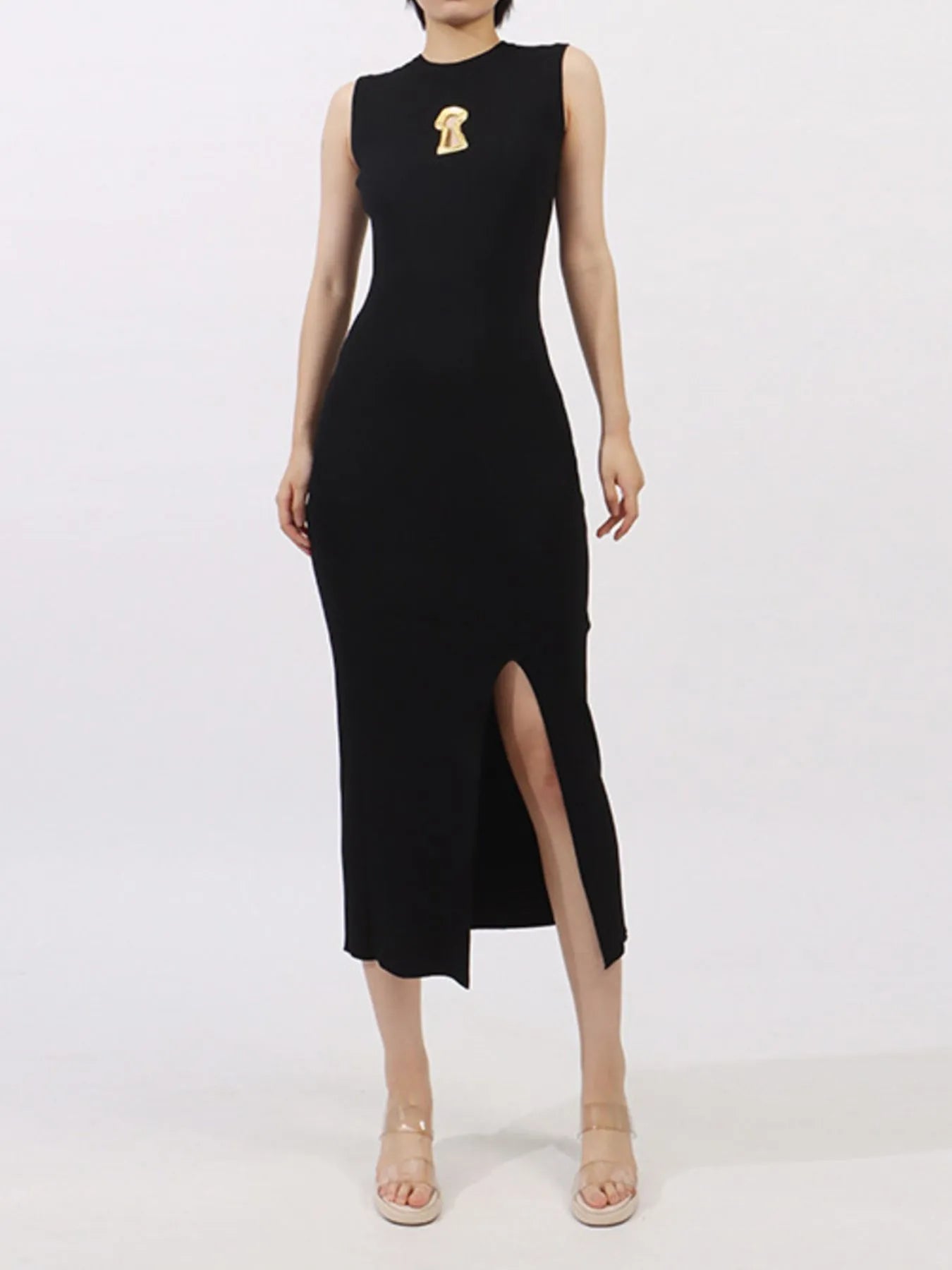 NEWYORKLISTED RUNWAY STYLE: Black sleeveless dress with a gold brooch on a white background