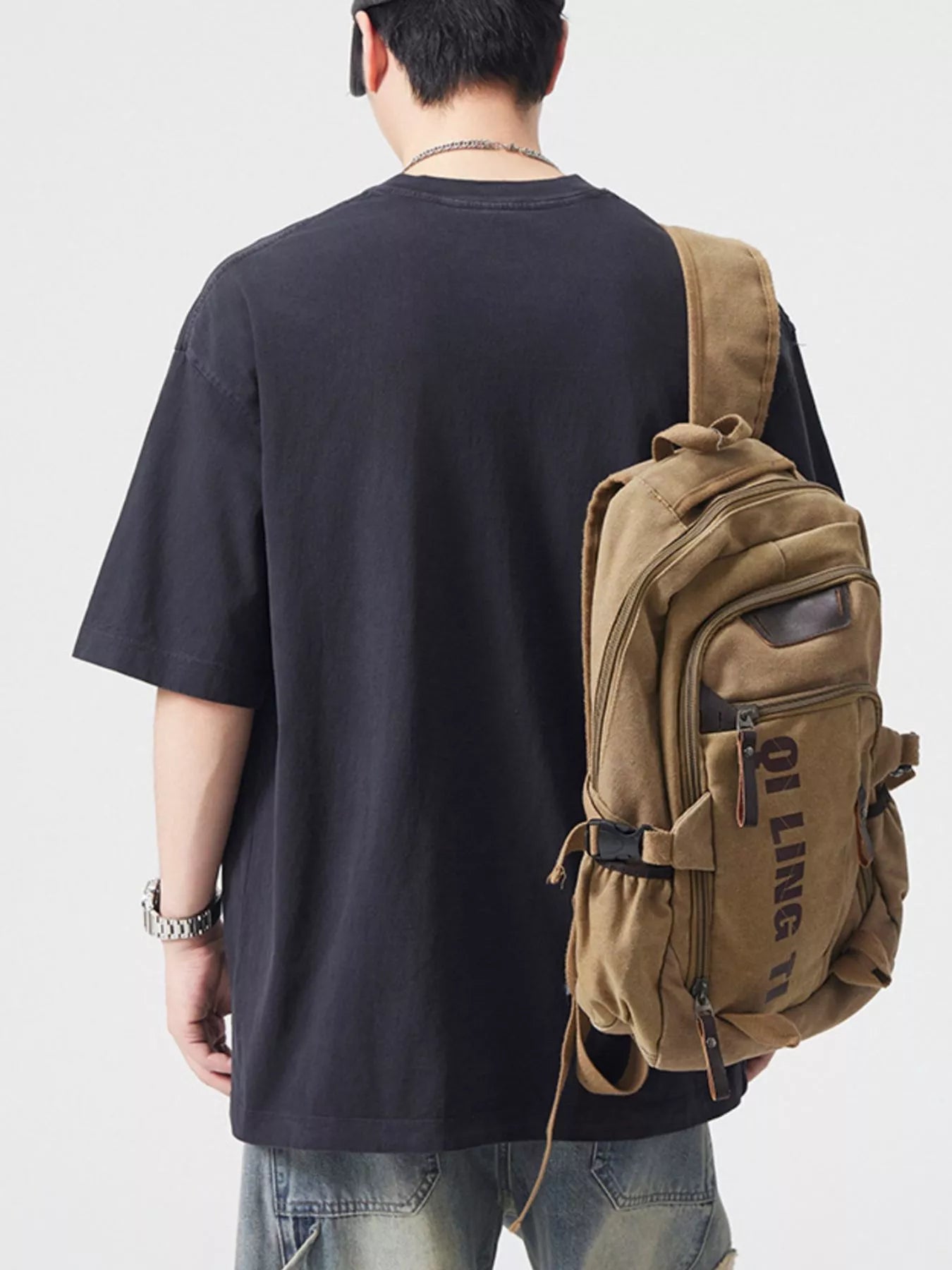 NEWYORKLISTED ATLAS MEN's COLLECTION: Person wearing a black t-shirt and brown backpack on a plain background