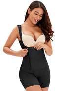 NEWYORKLISTED Intimate Apparel: Woman wearing a black shapewear garment with a beige bra on a white background