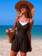 NEWYORKLISTED EDEN COLLECTION: Woman in a black romper and sun hat on a beach with blue sky and ocean.
