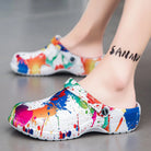 NEWYORKLISTED STYLE COLLECTION: Colorful splatter paint clogs worn by a person on a gray background