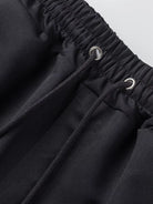 NEWYORKLISTED ATLAS MEN'S COLLECTION: Close-up of black pants with drawstring waistband on a light gray background