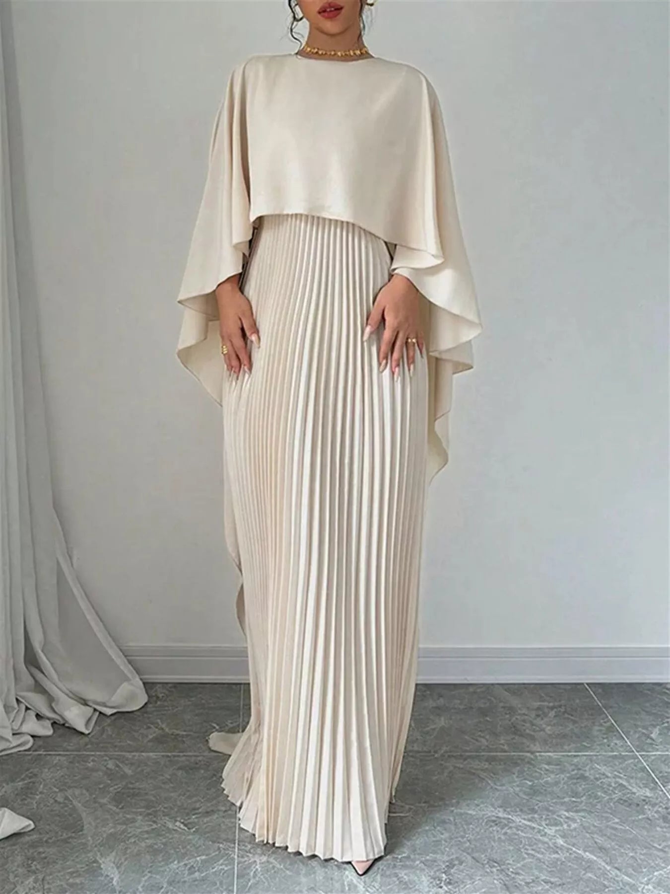 NEWYORKLISTED STYLE COLLECTION: Woman wearing a beige pleated dress with a matching top against a plain background