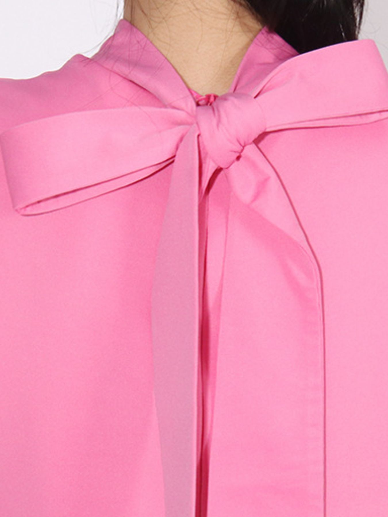 NEWYORKLISTED STYLE COLLECTION: Close-up of a pink blouse with a large bow detail on a white background